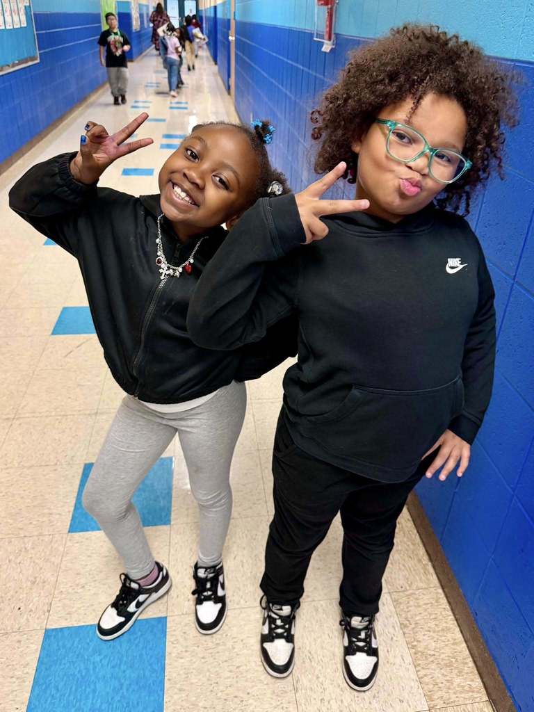Two Banneker students giving peace signs while both dressed in the same black clothes and shoes.