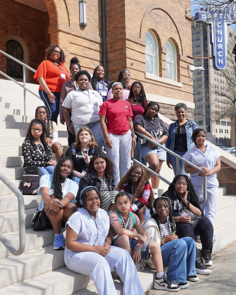 A group of female students sit on the steps outside the historic 16th Street Baptist Church in Alabama