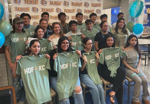 Graduating seniors hold up green t-shirts reading "HDF KC" after they were awarded HDF scholarships.