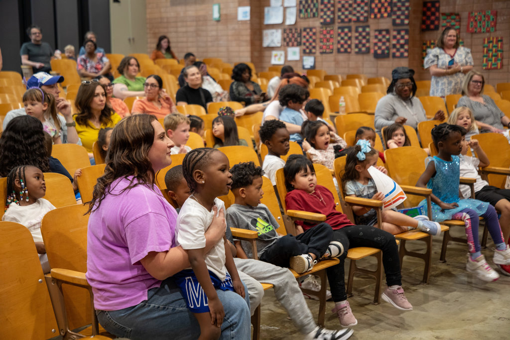 An auditorium full of pre-k students, teachers, and parents looking forward