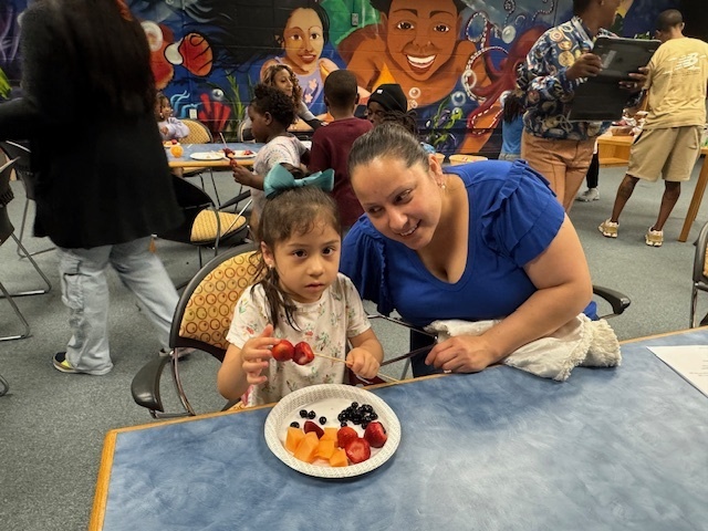 A mother and her daughter sitting at a table eating fruit