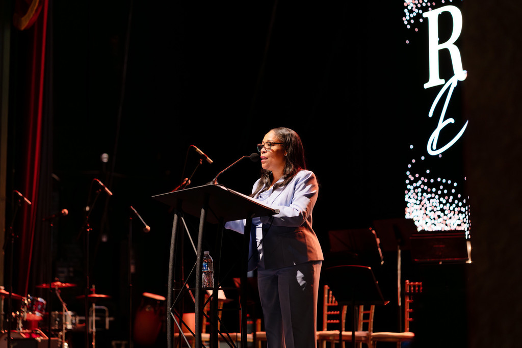 Superintendent Dr. Collier stands at a podium on a stage speaking to a crowd