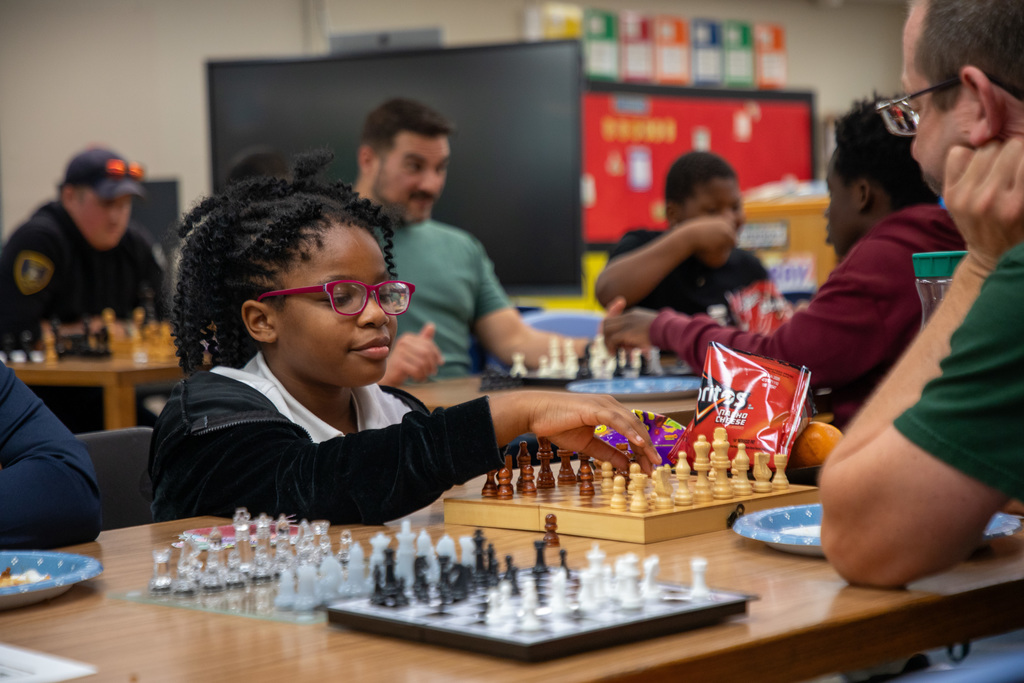 A young girl makes a move on a chess board
