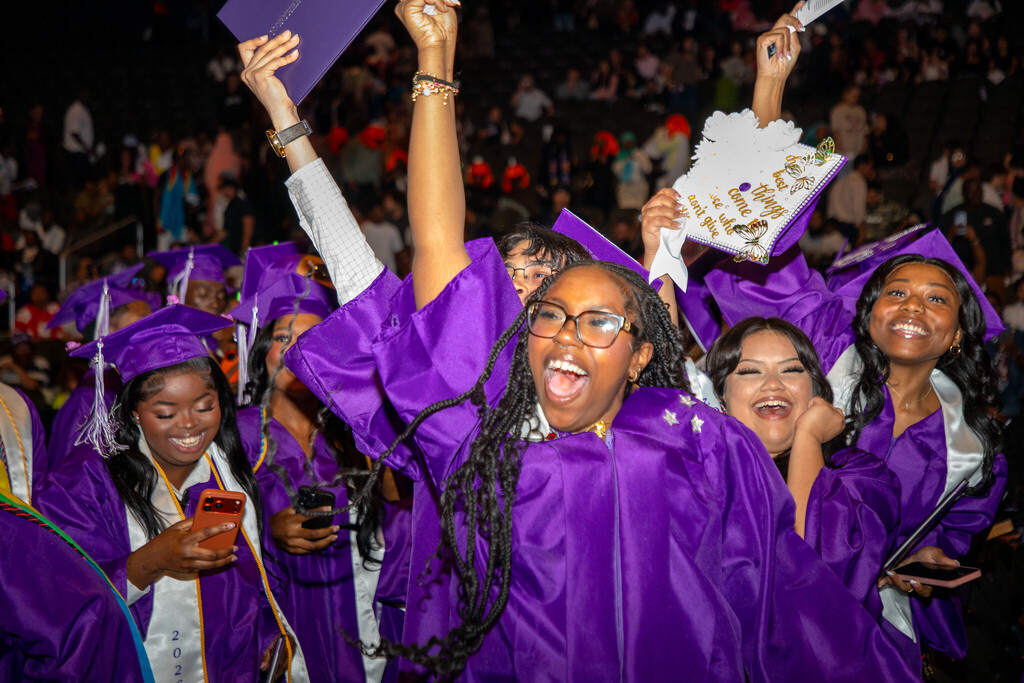 Students wearing purple robes celebrate graduating high school