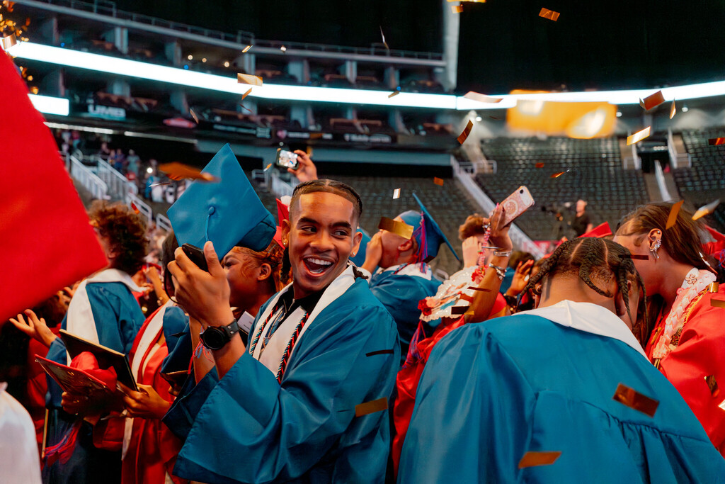 Students wearing blue and red robes celebrate graduating high school