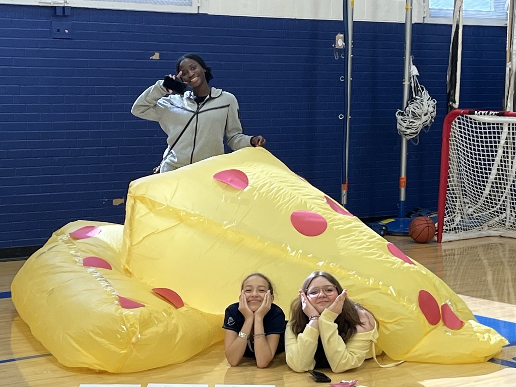 Students stand behind a handmade, cheese-shaped inflatable project