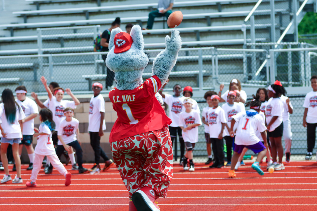 KC Wolf the chiefs mascot throws a football to a crowd of children