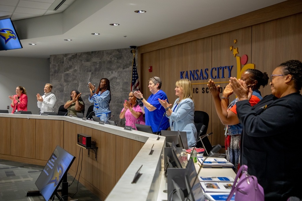 Members of the KCPS Board of Education stand and applaud Madison