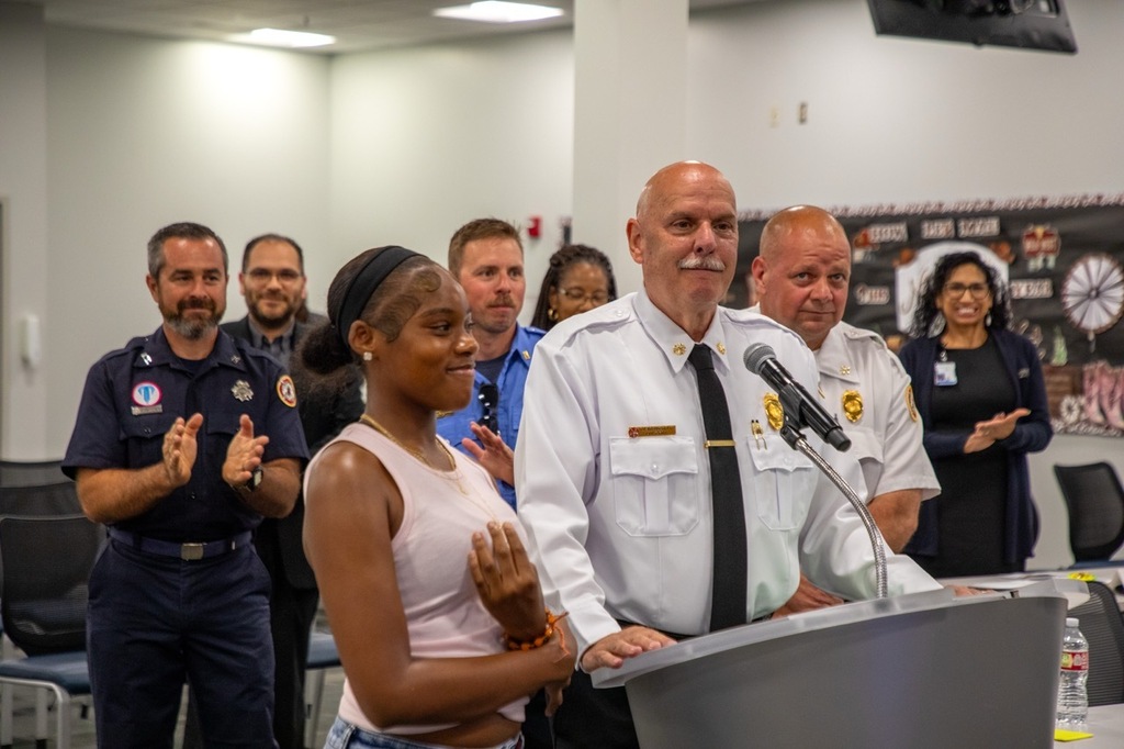 Madison Hill and a representative of KCFD stand at a podium to recognize Madison for an award