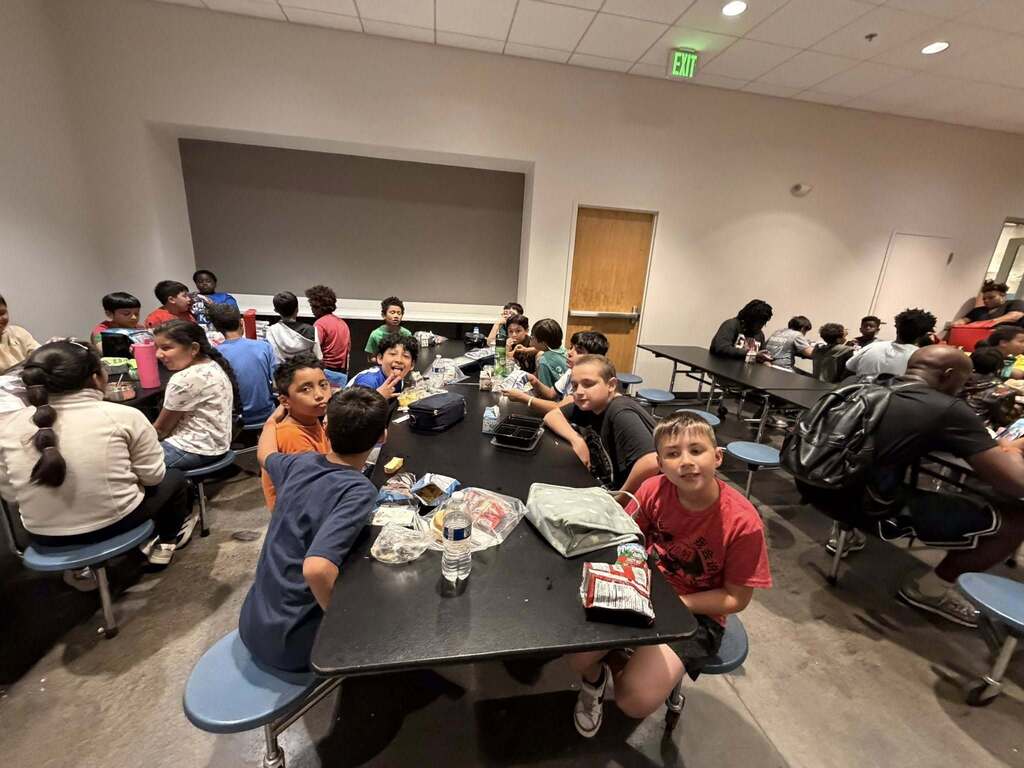 Students sit while eating lunch at a long table