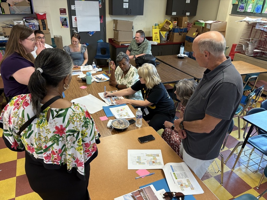 A group of adults sit at a table to discuss pre-construction updates on the Woodland/Whittier Empowerment campus