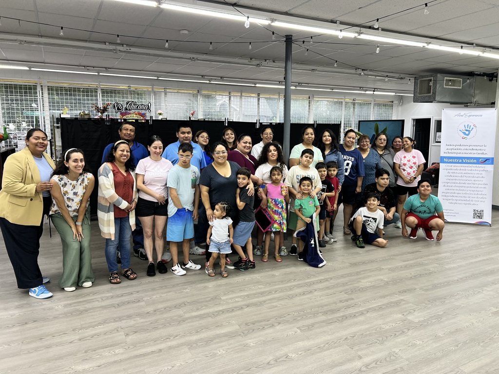 A large group of adults and their children stand smiling at the camera
