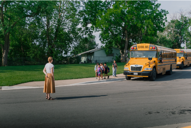 students  arriving to school, buses parked in front of school with students getting off of bus