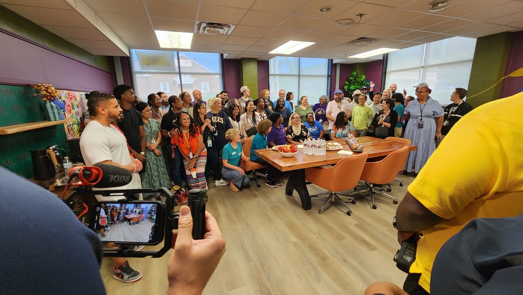 A large group of teachers group together to smile for photos during the unveiling of the newly redone teacher's lounge at Northeast Middle School