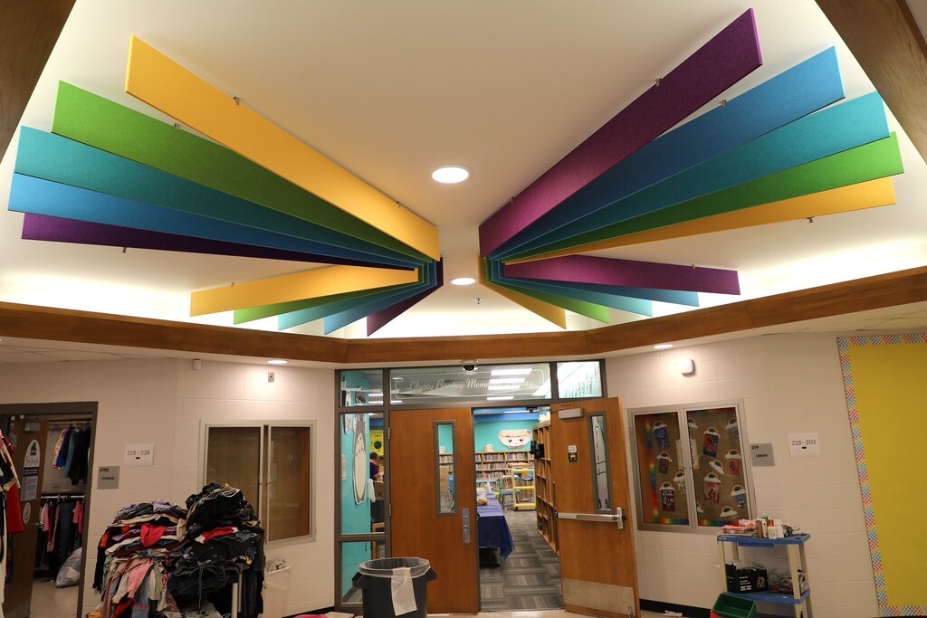 A look up at a ceiling with bright, multicolored baffles attached