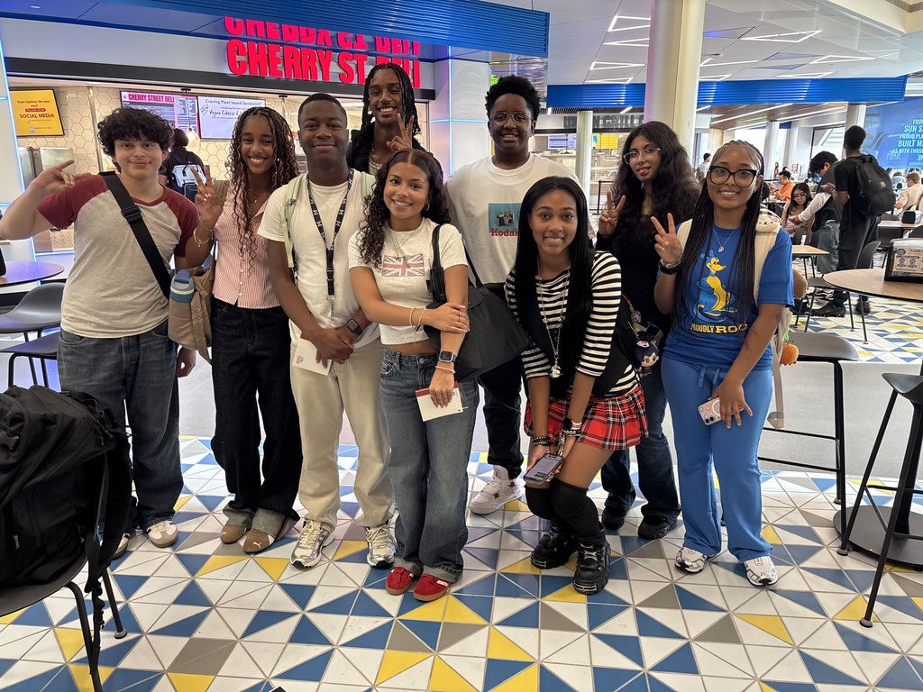 A group of nine young men and women gather together smiling at the camera