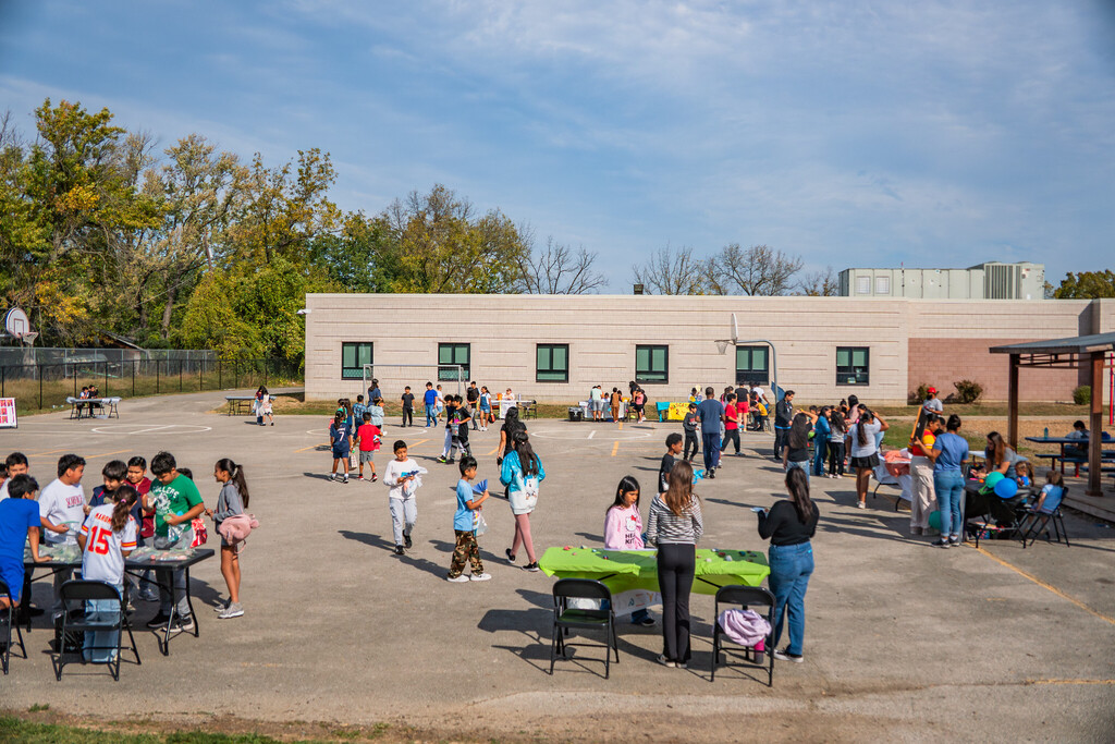 a distant photo of carver dual language with students, families, and teachers in the foreground completing activities at different stations