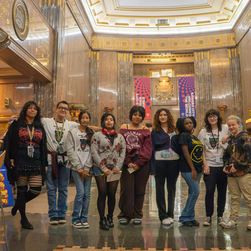 a group of students stand in a line smiling at the camera inside kc city hall