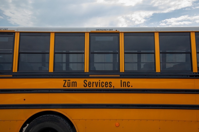 a school bus stretches across the photo with 'zum services, in' written on the side