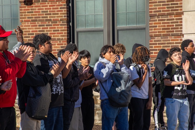 a group of teenagers stand in a row clapping