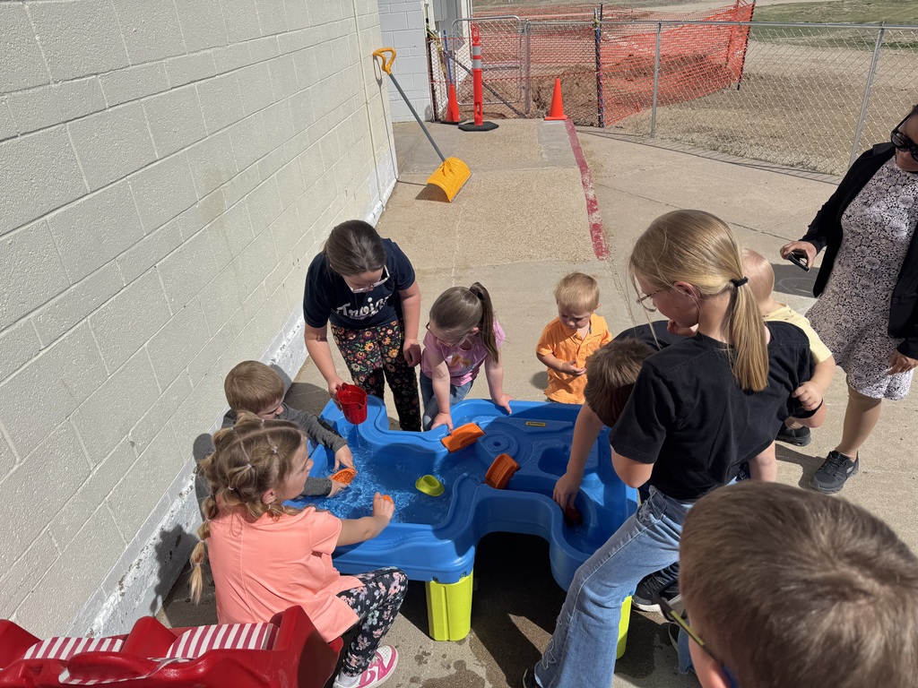 students gather around a water table at recess