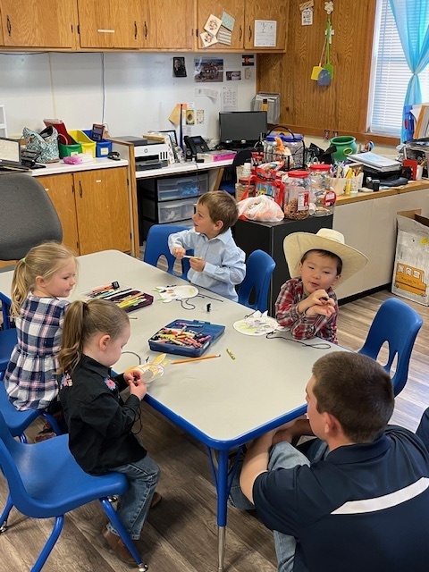 Preschoolers gather around a table to craft animal masks.