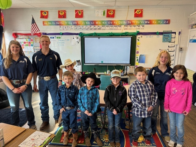 K-2nd grade students pose in an elementary classroom with FFA members.