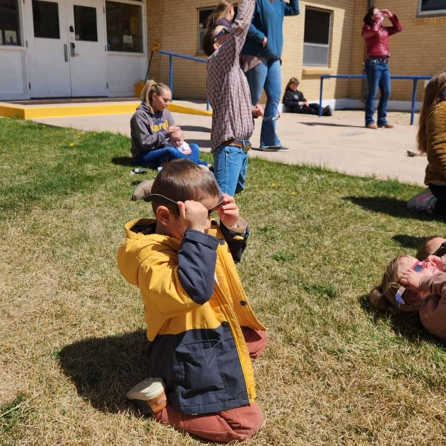 elementary students gaze at the solar eclipse from the front lawn