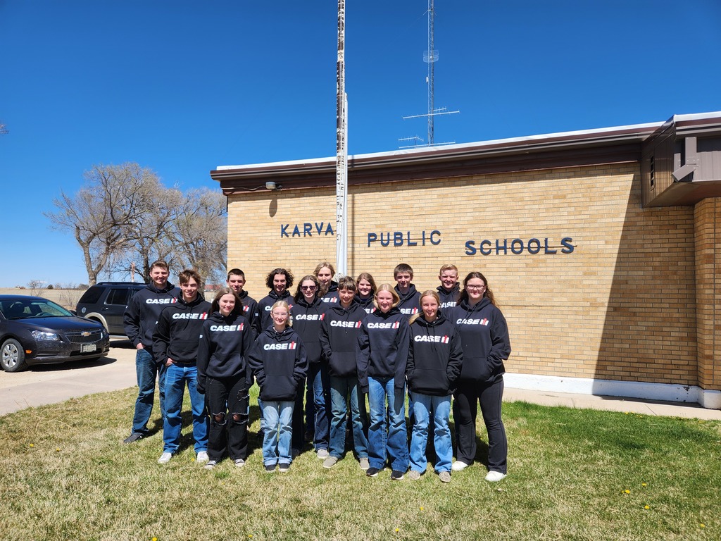 Junior high and high school students pose in CASE IH sweaters on the school's front lawn.