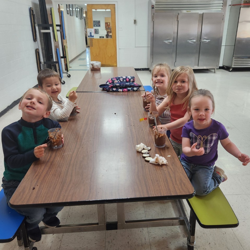 Preschool students eat dirt cakes in the cafeteria.