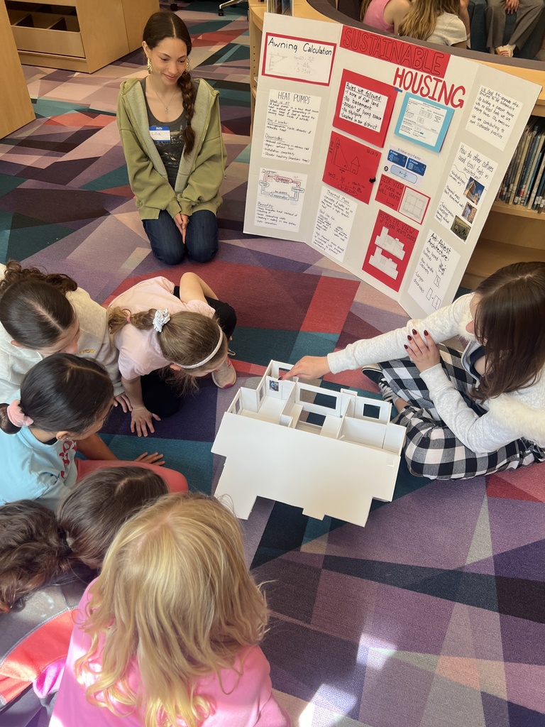 students sitting looking at a model house