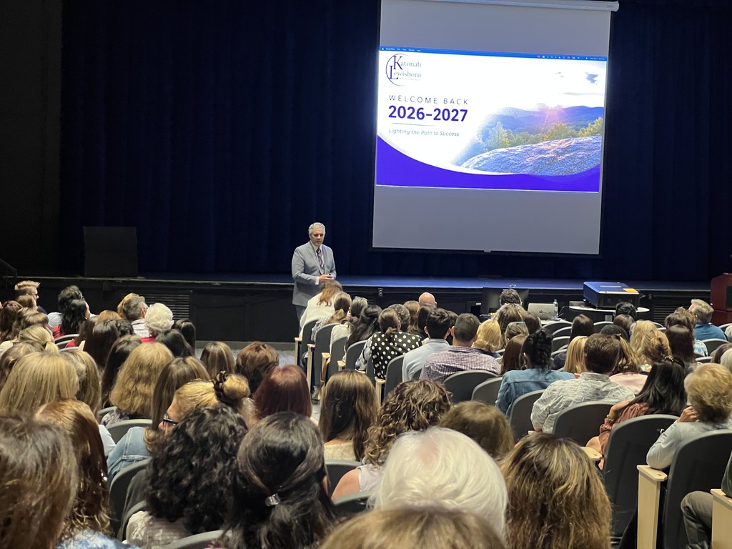 adult standing speaking to adults sitting in auditorium
