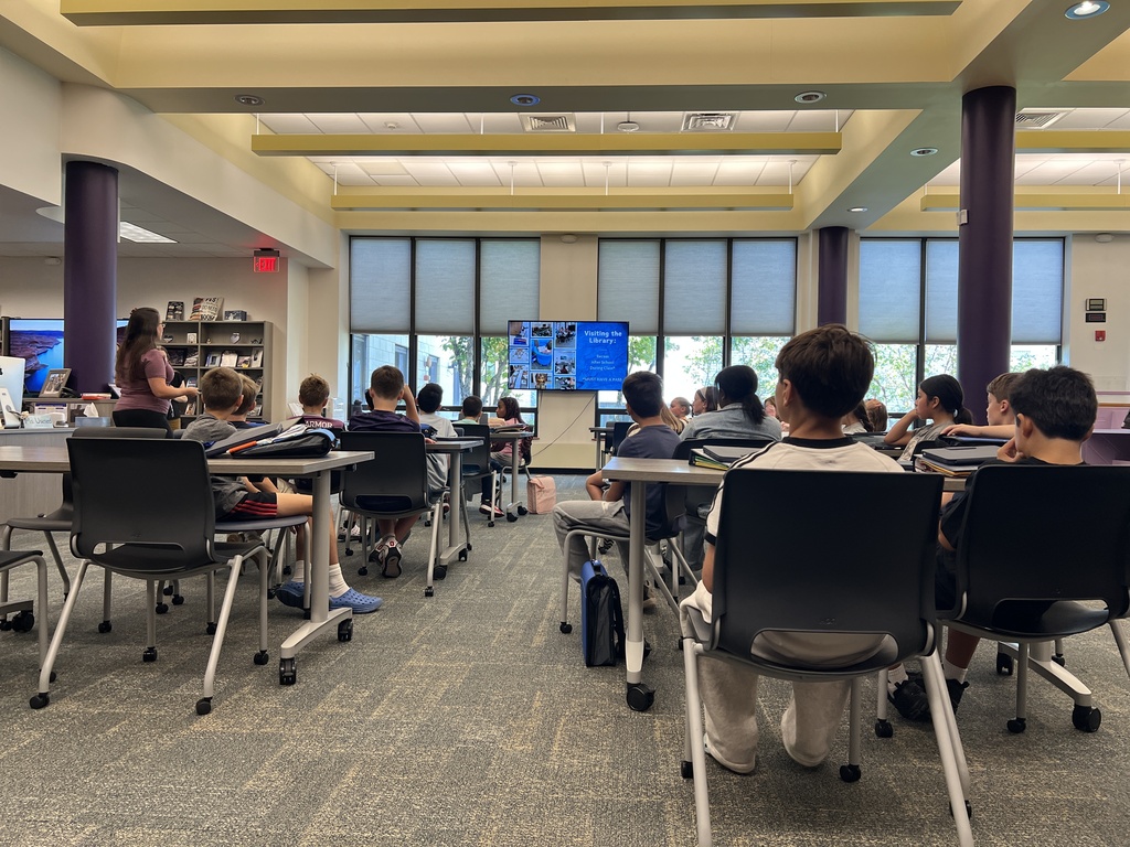 students sitting teacher standing looking at board 