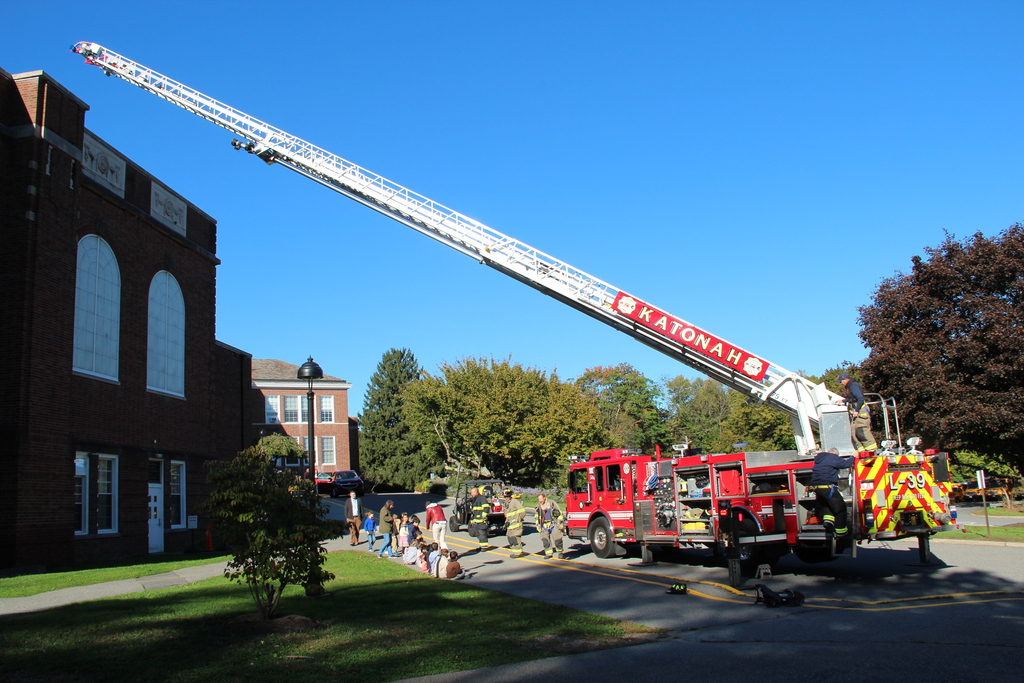 students watching firemen and firetruck outside 