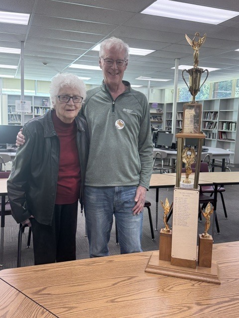 a woman and a man posing with a trophy