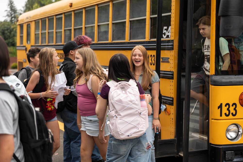 Kent School District students disembark a school bus on the first day of school.