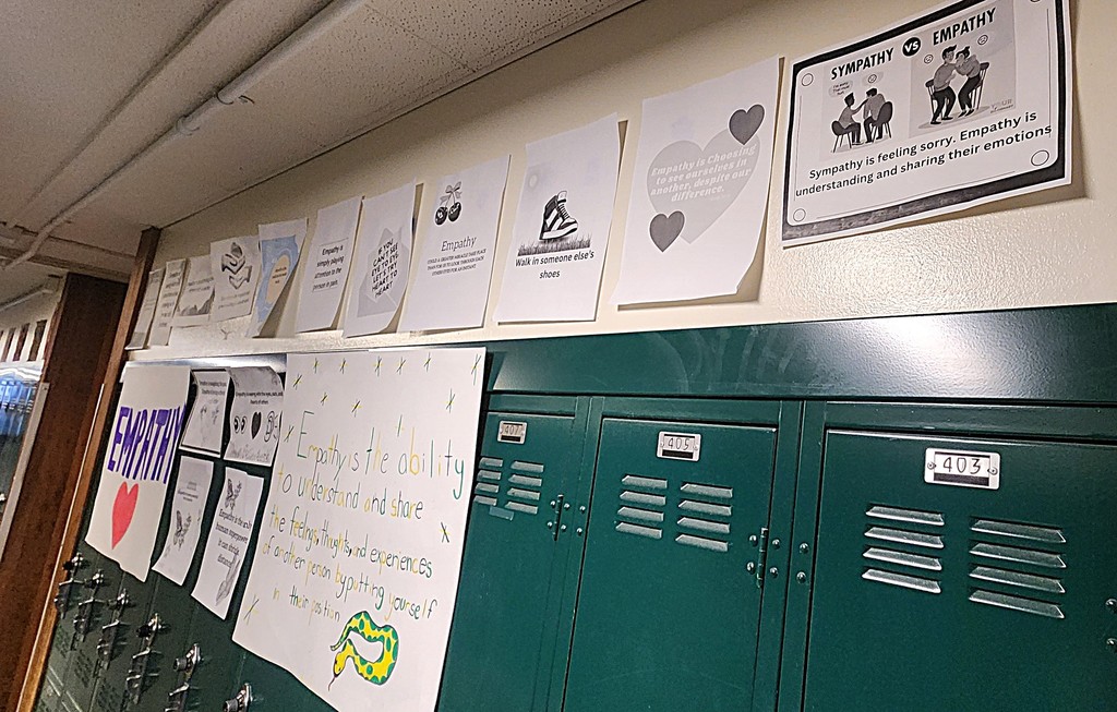 Pictures posted on a wall with lockers that showcase the word "Empathy"