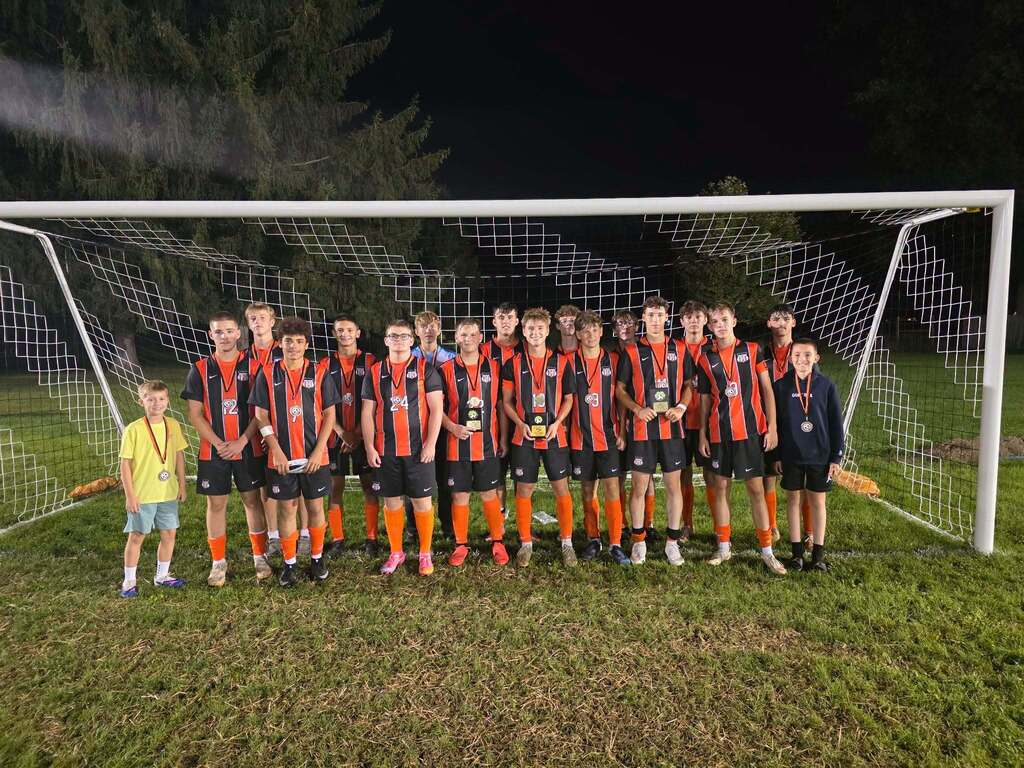Team stands with medals and trophies after winning tournament.