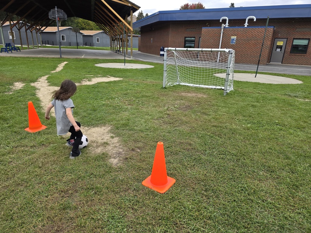 Students running up to shoot the soccer ball in the net.