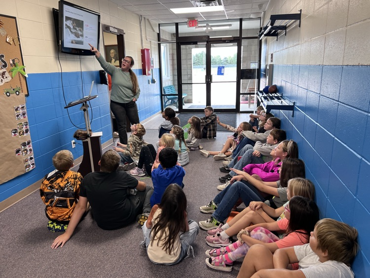 woman sharing information with group of children