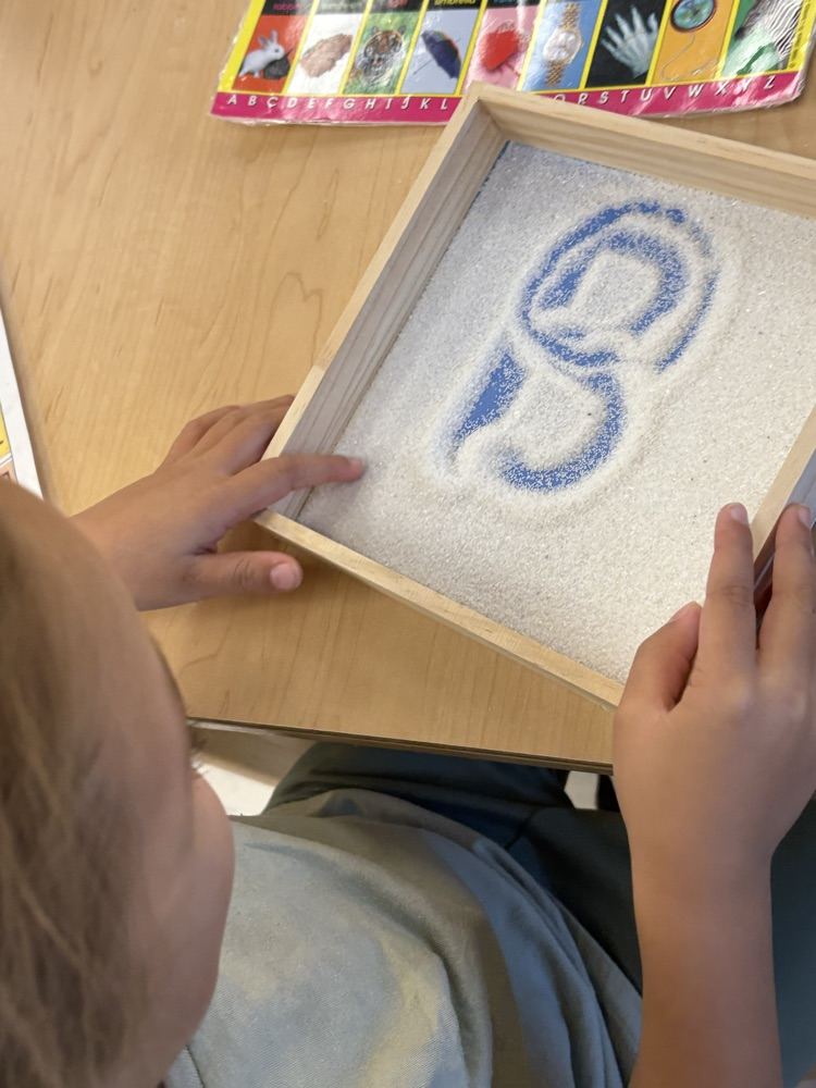 Working on our fine motor skills and learning to form letters in the sand.
