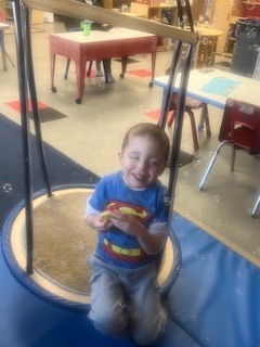 Pre K smiling while playing with bubbles.