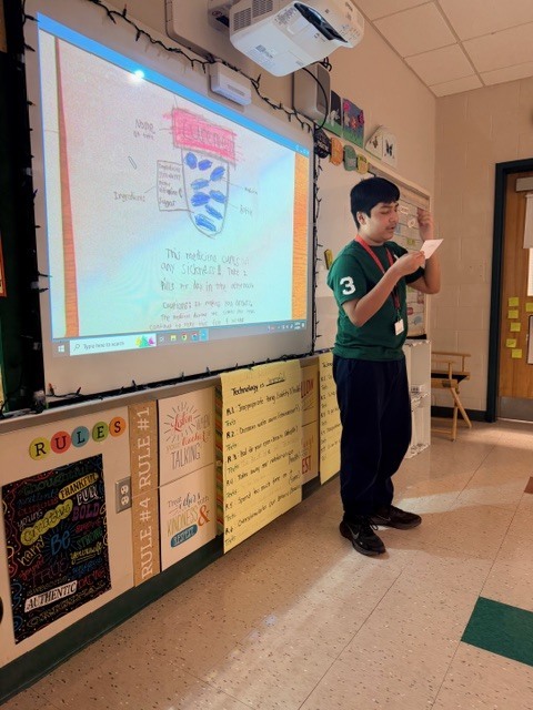 student reading from an index card at the board