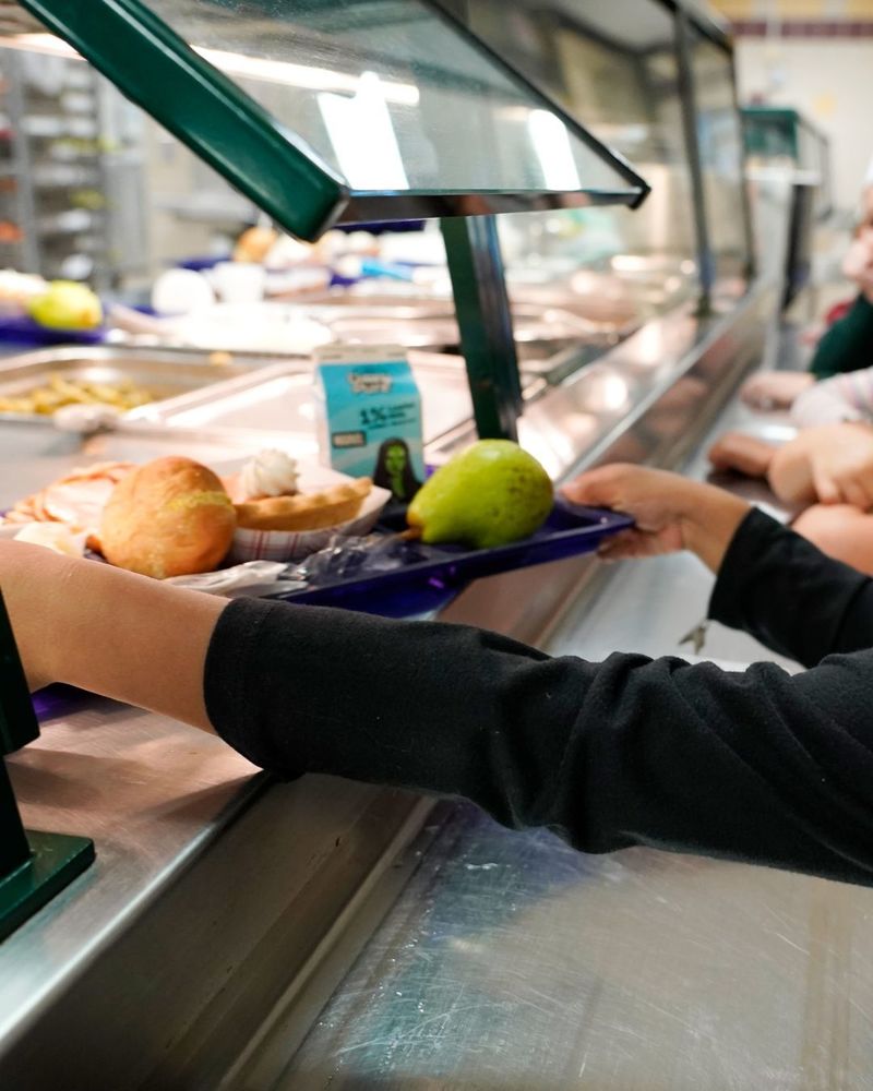 little hand grabbing a lunch tray in the school cafeteria