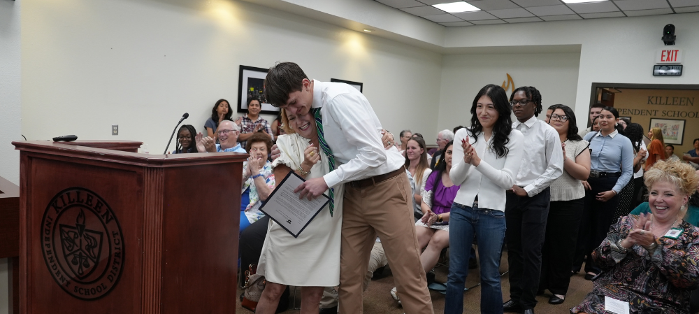 woman and young man hugging with other students applauding