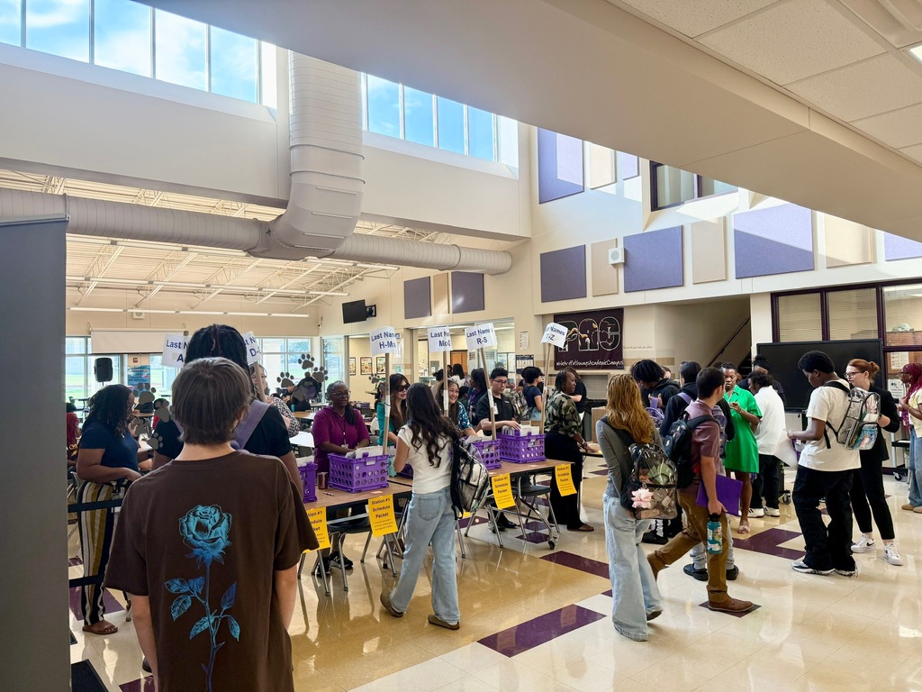 Students picking up supplies in cafeteria from staff. 
