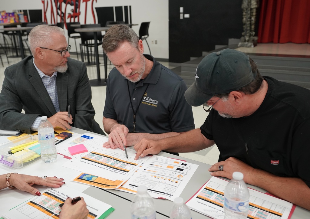 two men looking down at a paper making notes and talking
