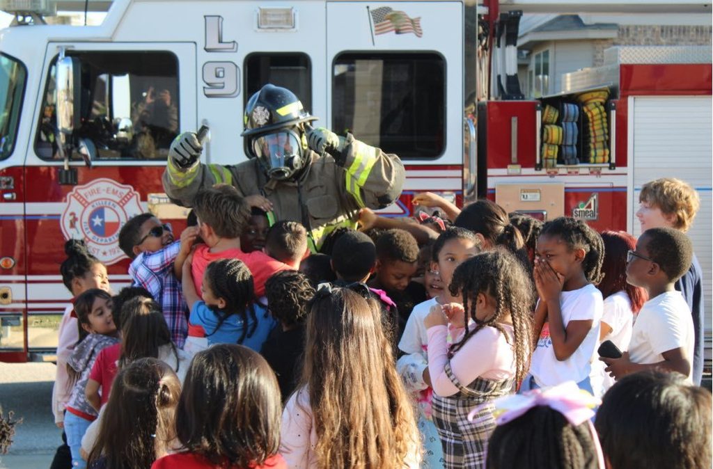 students hugging fire fighter