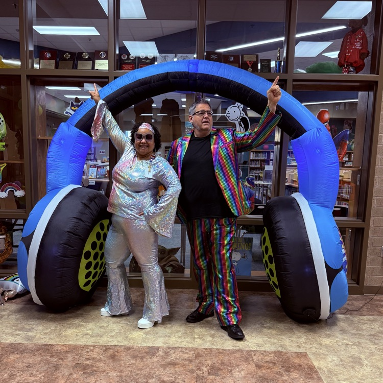 Man and woman in sequined outfits posing in disco stance