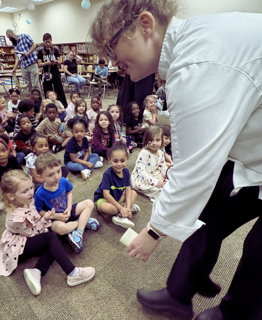 Children looking into mason jar held by chef